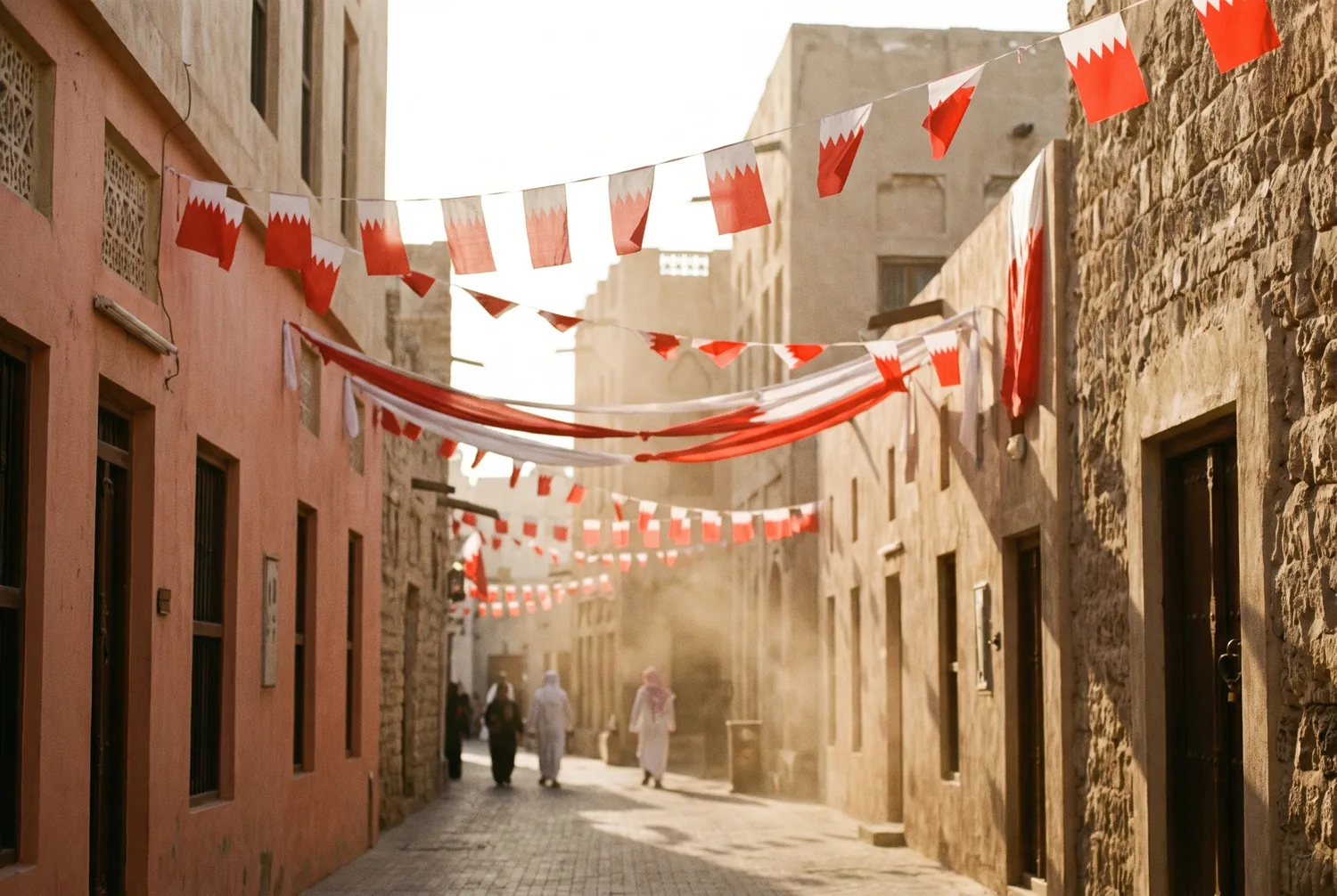 Red and white Bahrain National Day flags strung across a traditional street at golden hour