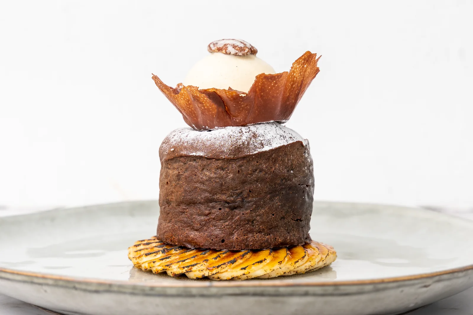 A plated chocolate dessert with vanilla ice cream and grilled pineapple, styled and shot in-house by TCCA